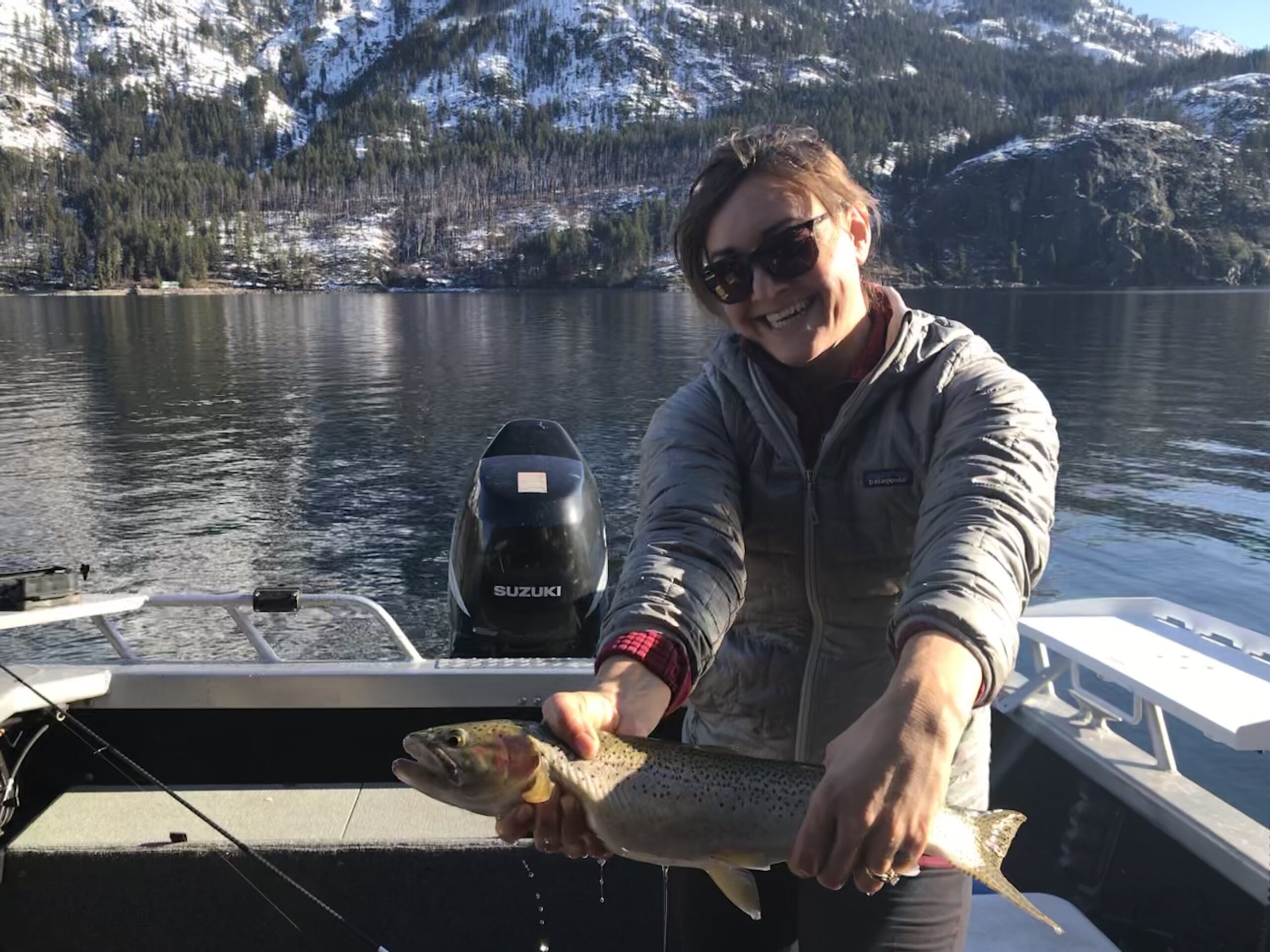 Emily Johnson holding a fish while sitting in a boat.